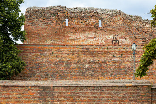 Ruins of the Teutonic Castle from the 13th century stand in Torun. Brick walls with arched openings and weathered surfaces create a clear medieval layout. 