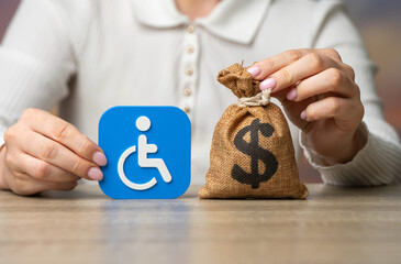Obraz premium Disability symbol and dollar money bag. Compensation for health damage, medical treatment grants, pensions and benefits. Social support and financial assistance.