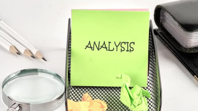 The word analysis appears on a bright green sticky note on a desk organizer