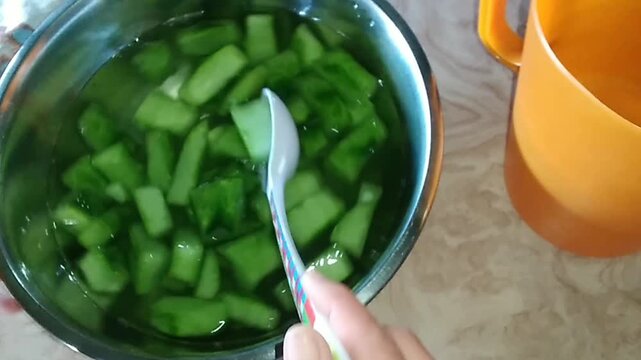 Nopal cactus pieces being transferred from bowl to pitcher with water