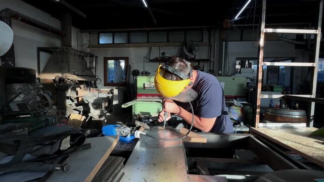 Professional worker in a protective mask using a tig welding torch on a steel sheet. Industrial manufacturing and skilled labor concept