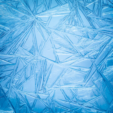 Ice frozen in intricate patterns of delicate crystals in sparkling blues. Detailed textures of real unique patterned crystal formations. Sparkling blue window frost or cold winter frosting background