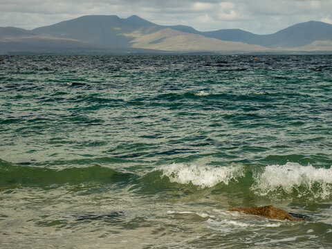 Distant hills frame rough sea with white-crested waves