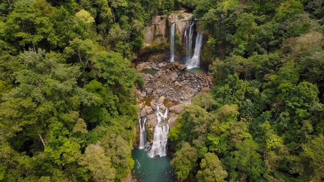 Nauyaca Waterfalls in Costa Rica by mossy cliffs and dense green rainforest