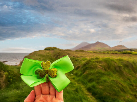 Green bow with shamrock sits in hand against Irish coast
