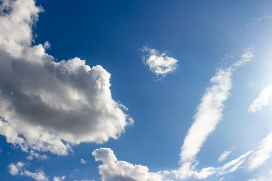 Vivid white fluffy clouds drifting across a deep blue sky during a sunny day, showcasing a serene atmosphere and bright natural light perfect for uplifting background designs