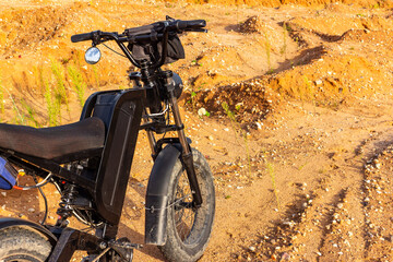 Modern black electric bike parked on a rough sandy off-road terrain, showcasing rugged tires, solid suspension, and powerful build designed for adventurous outdoor riding sessions © PhotoChur