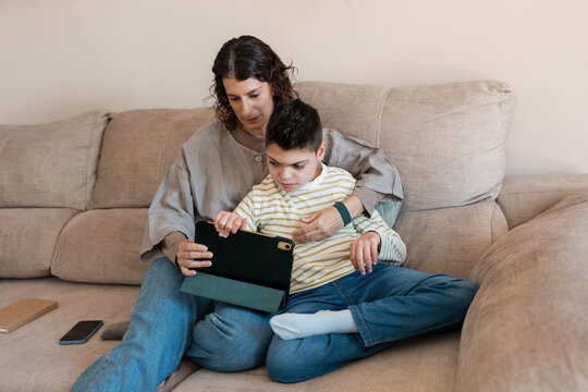 Mother and son with cerebral palsy learning on tablet