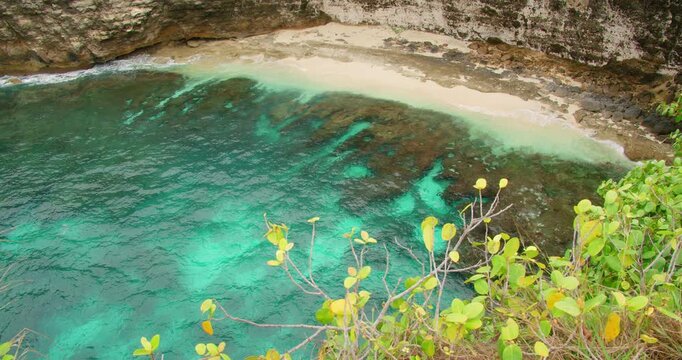 Top down view turquoise ocean water meets white sand beach and dark rocky seabed Nusa Penida