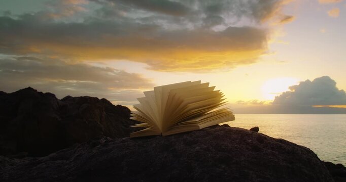 Open Book Placed on Rocky Shore with Dramatic Sunset Clouds Over Sea