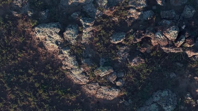 Top down aerial shot pulling back over rugged volcanic rock and dark craggy basalt textures in twilight, highlighting raw geological patterns and barren terrain.