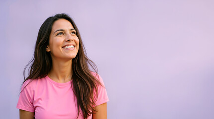 Fototapeta premium Smiling young woman looking up with a happy expression. Cheerful female portrait against a solid purple background. Copy space for text