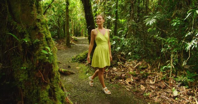 Woman tourist walking along a Costa Rica rainforest path surrounded by bright tropical greenery