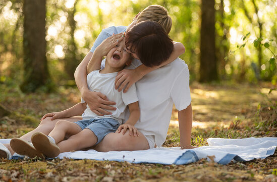 Mother embracing sons in a warm summer forest, showing love, care, and family bond during golden hour