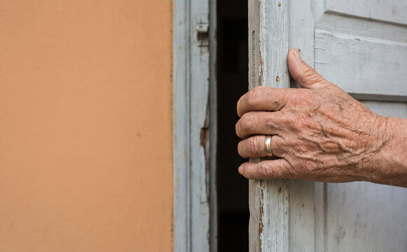 Elderly man holding a wooden door, symbolizing age, wisdom, and opening a new chapter of life