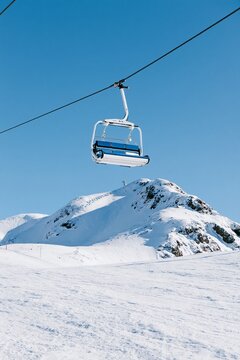 Empty chairlift above a snowy mountain slope under a clear blue sky at a winter ski resort