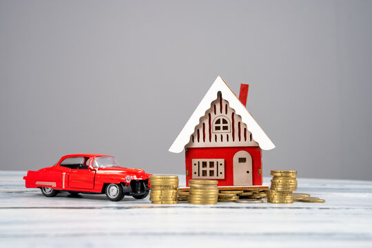 Stack of coins, toy house and car on table, saving money for future, business and finance concept.
