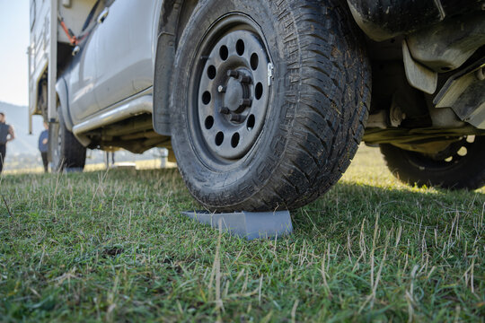 A wheel chock installed under a car wheel.