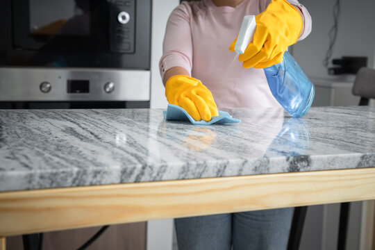 Washes the kitchen table with gloves