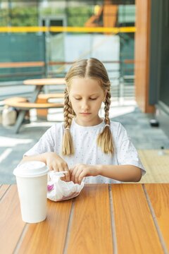 Child opening wrapped fast food meal at outdoor cafe