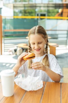 Girl enjoying burger at outdoor cafe