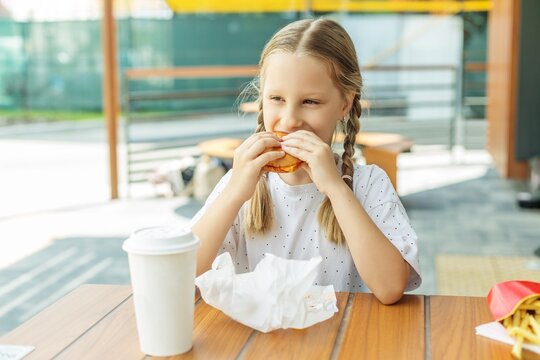 Child eating burger at outdoor cafe