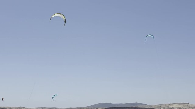 Multiple kitesurfers ride and maneuver across the waters of Keros Beach near Surf Club Keros on Lemnos Island, Greece, in August.