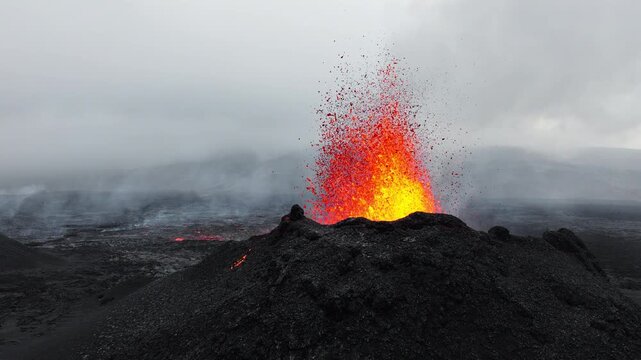 Active lava fountain erupting from volcanic vent with glowing molten flow over dark scoria rim, drifting ash, heat haze, and rugged barren terrain, with lava, eruption, volcano, magma detail