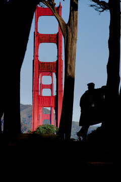 Golden Gate Bridge framed by cypress trees with a silhouetted person in Presidio, San Francisco, California. g.