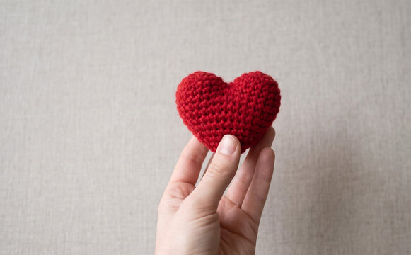 Person holding a handmade red crocheted heart symbolizing love and affection for a Valentine day gift