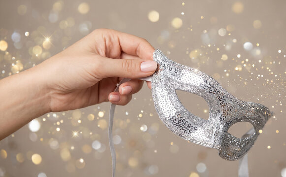 Woman holding a sparkling silver masquerade mask for a festive holiday party or carnival celebration