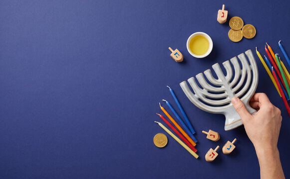 Hanukkah celebration setup with menorah, colorful candles, dreidels, and chocolate coins on a blue background