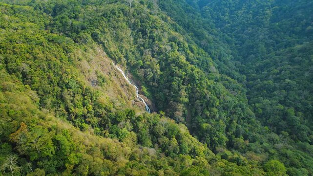 Distant view of cascading waterfall on a forested cliff in Costa Rica