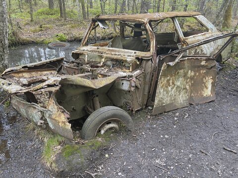 Heavily rusted car in the forest, disintegrated and overgrown by nature, Ryd, Kyrk&ouml; Mosse car cemetery, Tingsryd, Sweden
