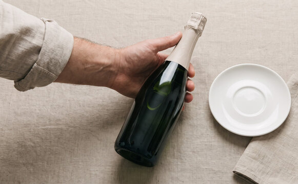 Man holding a bottle of champagne over a table with a white plate for celebration concepts