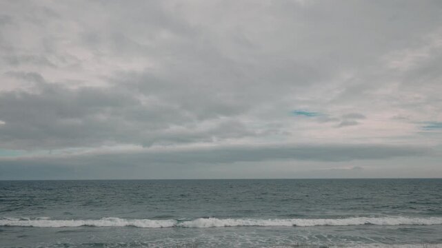 A grassy field with a gray sky and sea in the background