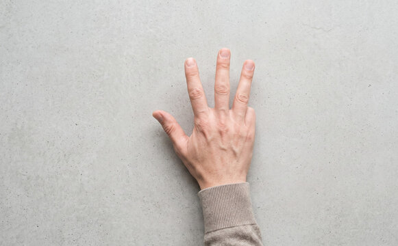 Adult caucasian male hand counting four fingers showing number gesture on grey background