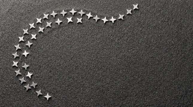 Miniature silver stars on fine charcoal sand cenital flat lay