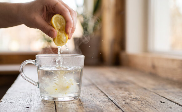 Woman squeezing fresh lemon into a hot cup of water for a healthy morning routine