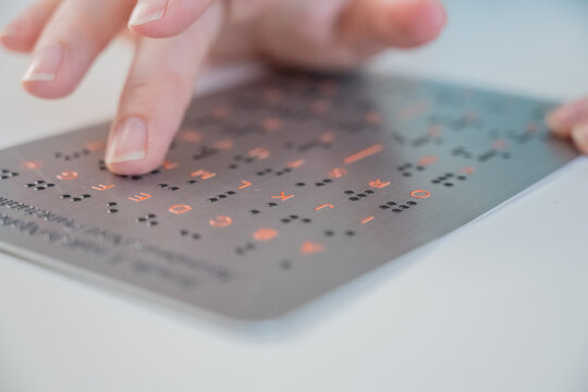 A blind woman learns the English alphabet from a braille sign.