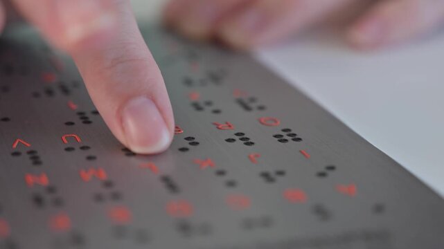A blind woman learns the English alphabet from a braille sign.