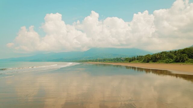 Lush jungle meets calm ocean waters as woman walking at Marino Ballena Park in Costa Rica