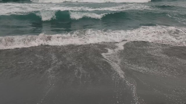 Intermittent Waves Breaking on a Gray Sandy Beach
