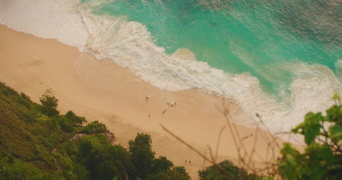 Aerial view of turquoise sea foam meeting sandy shore in tropical Bali Nusa Penida