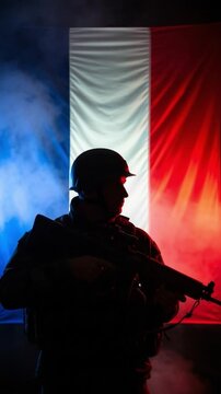 Silhouette of a male French soldier in uniform with a rifle standing in front of the national flag in smoke, representing patriotism and national defense