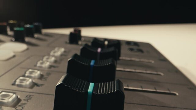 Music studio close up, Close up hands shot of sound engineer using mixing console, remote control for adjusting sound, audio mixer. Musician creates music, makes remix for DJ set. Sound