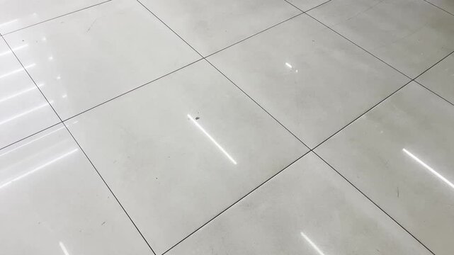 Glossy marble tile floor with geometric overhead light reflection