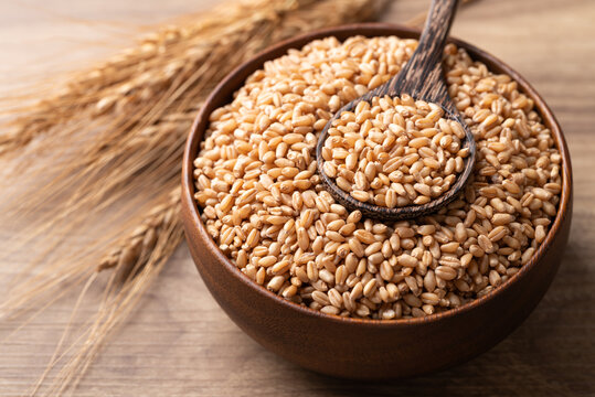 Whole wheat grain in a wooden bowl with spoon, Food ingredients