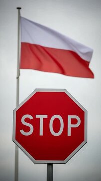 Stop sign with the Polish national flag waving in the background symbolizing national regulations, traffic rules and political protest concepts