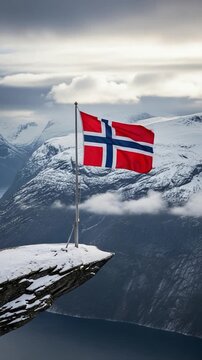 Norwegian flag flying proudly over a snowy mountain cliff overlooking a deep fjord in winter representing national pride and scenic travel adventures